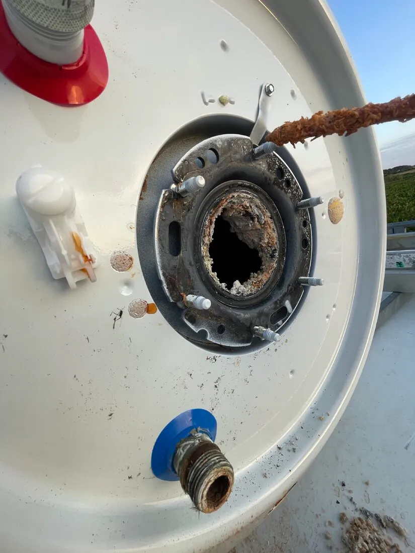 Trappe de visite ouverte sur un chauffe-eau : bride, joint et goujons pris dans le tartre avant remplacement