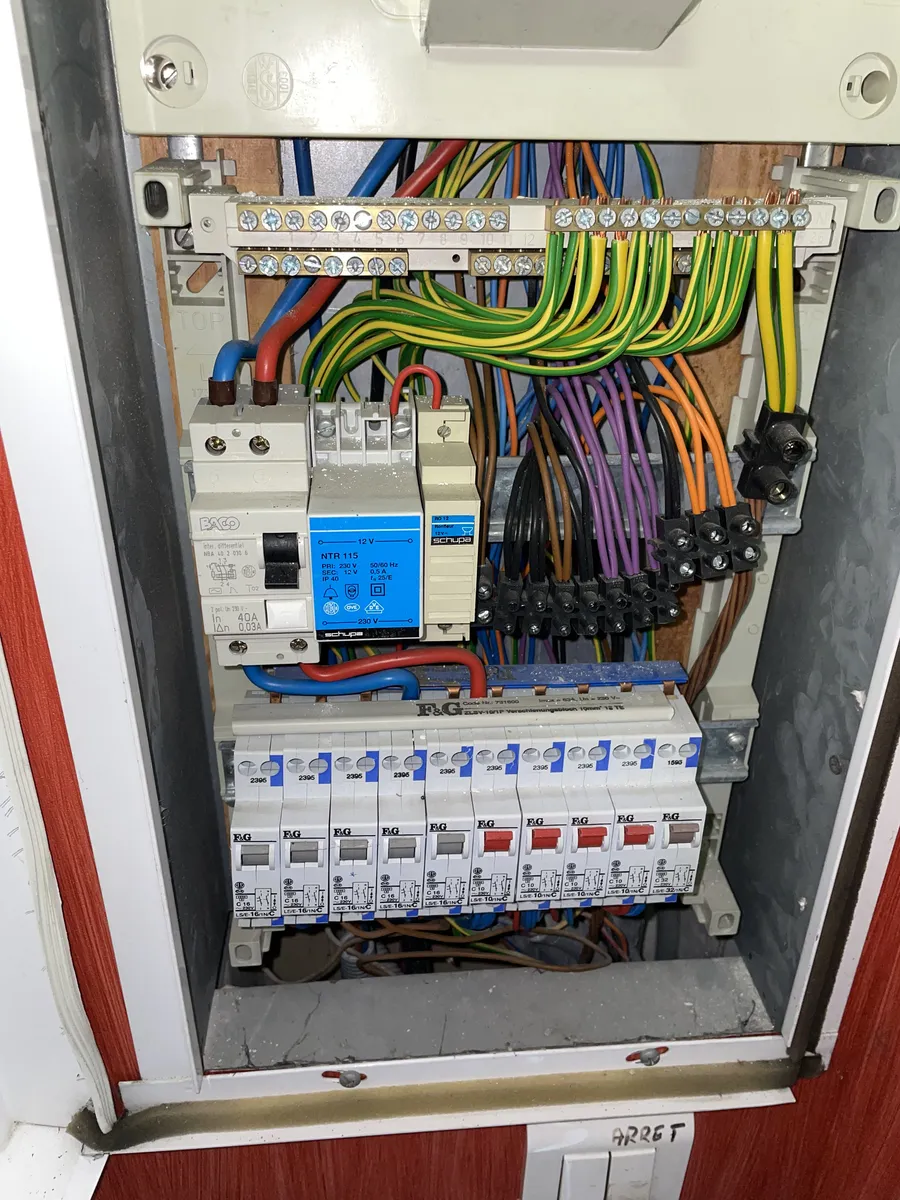 Tableau électrique ancien relevé dans un logement à Montpellier : disjoncteurs d'origine, raccordements par dominos et bornier vieilli sur support bois